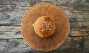 Hamburger z sezamem na drewnianej desce.